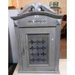 A 21 1/2" decorative painted wood wall cabinet with arched top and panelled door