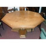 A 5' 3" polished oak octagonal tilt-top dining table set on a heavy moulded pillar with applied
