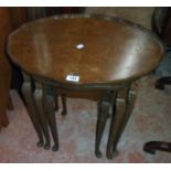 A nest of three walnut effect tea tables, the largest with shaped top