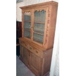 A 4' 3" late Victorian waxed pine two part dresser with moulded cornice, plate shelves enclosed by a