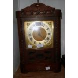 A stained oak cased American shelf clock with brass and silvered dial, visible pendulum and beaded
