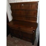 A 4' Ercol two part polished elm dresser with two shelf open plate rack over a base with two drawers