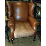 A 1998 Laura Ashley wing back armchair upholstered in brown hide leather, set on polished wood
