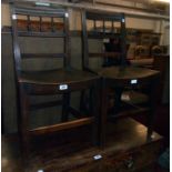 A pair of antique stained wood hall chairs with spindle set backs and solid curved seat panels,