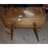 A vintage polished oak work box with fold-out top enclosing a tray fitted interior, set on slender