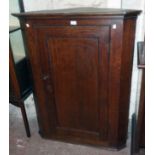 A 36" late Georgian polished oak corner cupboard with canted sides and scalloped shelves enclosed by