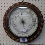 A 9" diameter late 19th Century carved oak framed aneroid wall barometer with rope twist border
