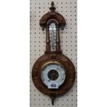 A late Victorian decorative carved walnut cased wall barometer/thermometer with printed ceramic
