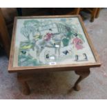 A 20 1/2" 20th Century stained beech tea table with a hunting scene woolwork panel under glass to