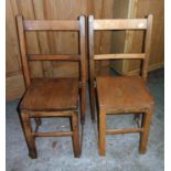 A pair of vintage elm school chairs with moulded solid seat panels and simple square supports
