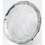 A 10 1/2" diameter silver salver with cast gadrooned rim, set on triple scroll feet - London 1959