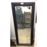 A heavy stained hardwood framed bevelled oblong wall mirror with moulded decoration