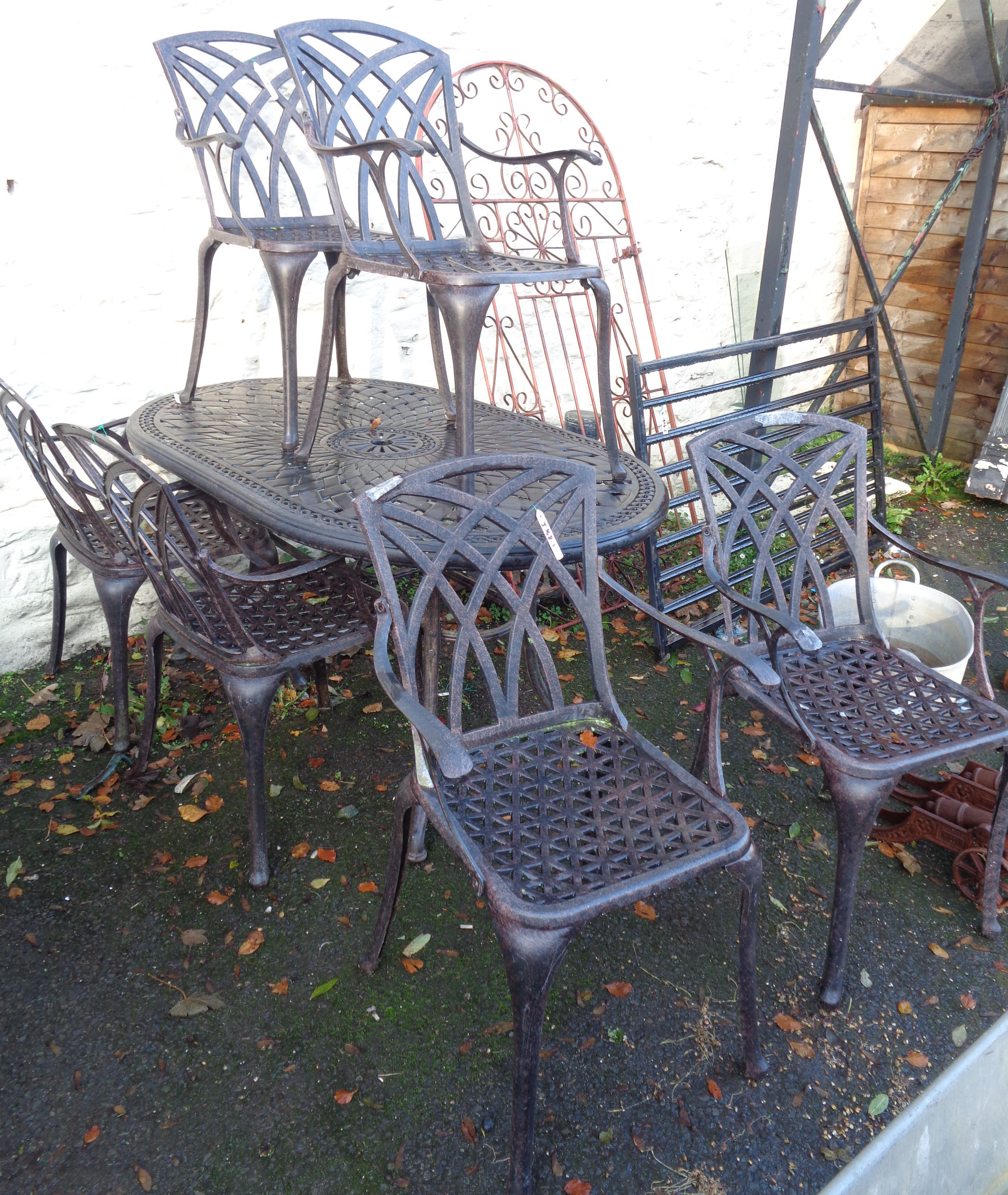 A cast aluminium garden table and six chairs - table length 5'