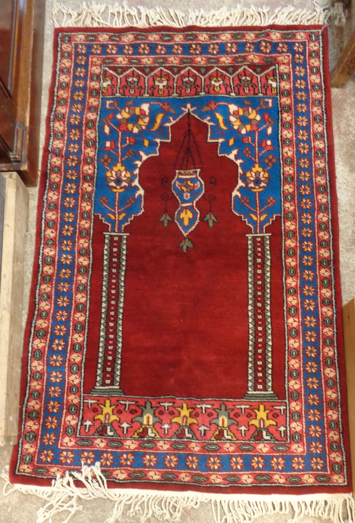 A small prayer rug with mihrab and mosque lamp within repeat floral decoration on red ground - 31" X