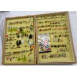 A folding wooden case containing a collection of assorted salmon and trout fishing flies