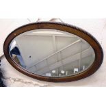 An early 20th Century polished oak and beaded framed bevelled oval wall mirror
