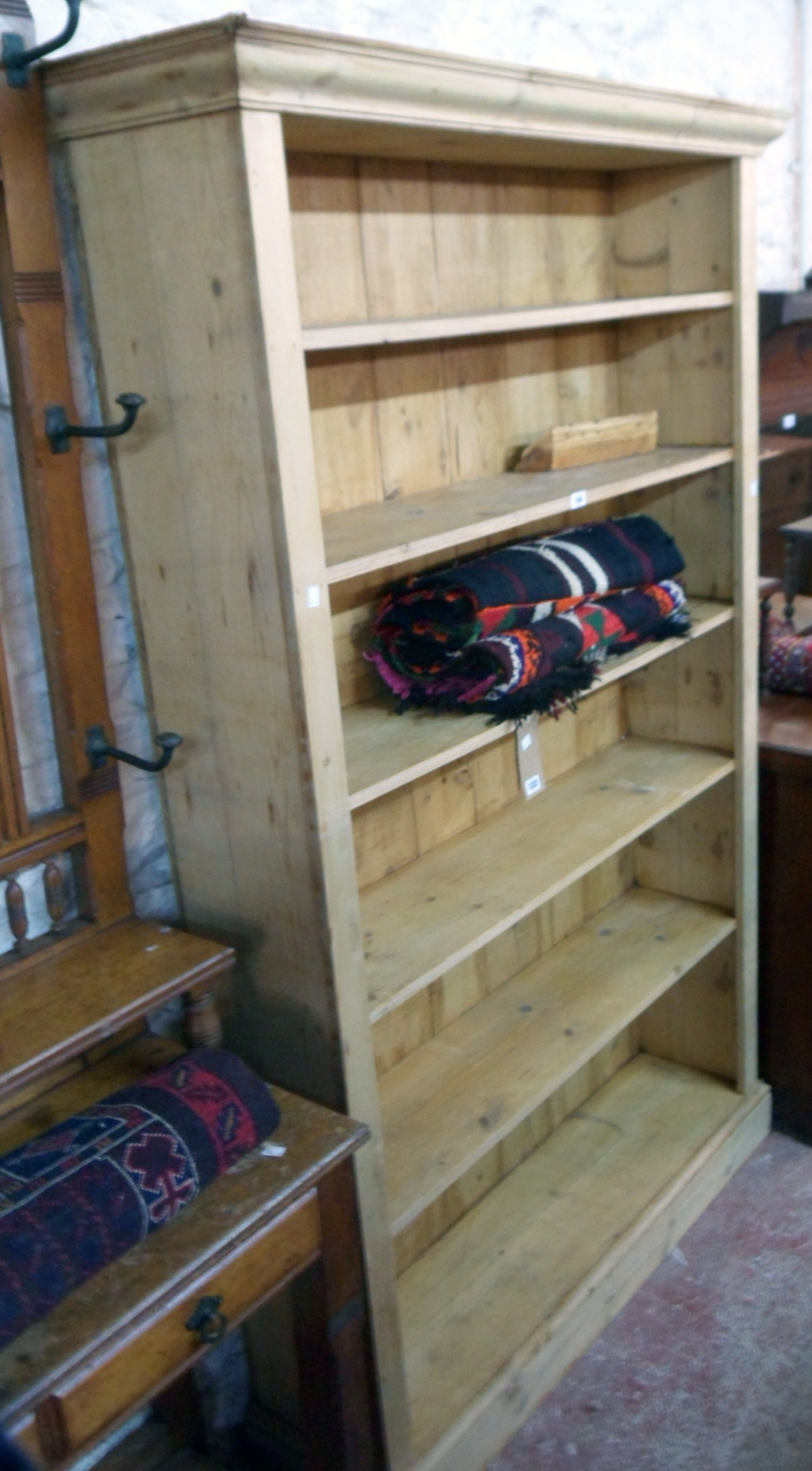A 4' 3" stripped pine six shelf open bookcase with moulded cornice and plinth base - 6' 9" high
