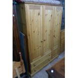 A 4' 2 1/2" modern polished pine triple wardrobe with hanging space enclosed by panelled doors