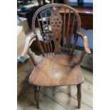 An antique elm wheel back elbow chair with solid moulded seat, set on turned supports