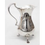 A silver baluster cream jug with cast handle, set on stylised paw feet - London 1928