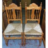 A pair of waxed pine framed spindle back dining chairs with woven rush seat panels and turned