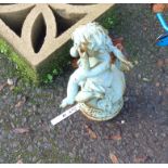 A small painted cast iron garden cherub weeping atop a finial