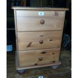 A 17 1/2" modern polished pine bedside chest of three drawers, set on turned feet