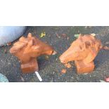 A pair of cast iron horses' heads with rusted finish