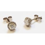 A pair of unmarked high carat white metal stud ear-rings, each set with central diamond within a