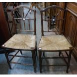 A pair of old stained beech framed spindle back standard chairs with woven rush seats and slender