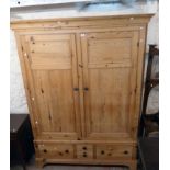 A 5' 5 1/2" old waxed pine double wardrobe with moulded cornice, hanging space enclosed by a pair of