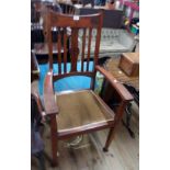 An early 20th Century stained mixed wood framed high stick back elbow chair with incised roundel