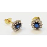 A pair of import marked 750 gold stud ear-rings, each set with central oval dark sapphire within a