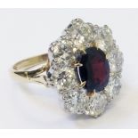 A marked 18ct. yellow metal ring, set with central 8mm oval ruby within an eight stone diamond