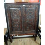 A 34" 19th Century stained and carved oak cabinet on stand with adjustable shelves enclosed by a