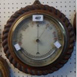 A 11 1/2" diameter Victorian carved oak rope twist border framed wall barometer/thermometer with