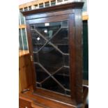 A 26 1/2" antique oak wall hanging corner cabinet with astragal glazed panel door and canted
