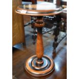 A reproduction pedestal table with antiqued finish, turned pillar and circular base