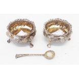 A pair of silver salts with embossed decoration and parcel gilt interiors, set on paw pattern feet -