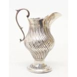 A Victorian silver reeded baluster shaped cream jug with cast scroll handle and embossed pedestal