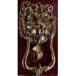 A brass lion mask door knocker