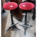 A pair of painted cast aluminium framed Victorian style bar stools with upholstered seats, footrails