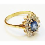 An import marked 375 gold ring, set with central oval pale blue sapphire within a white paste