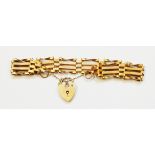 A yellow metal four bar gate-link bracelet with hallmarked 375 gold heart shaped padlock