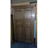 A 4' 2" waxed pine double wardrobe with moulded cornice and hanging space enclosed by a pair of