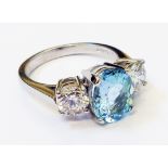 A hallmarked 950 platinum ring, set with central oval aquamarine, flanked by two 0.5ct. brilliant