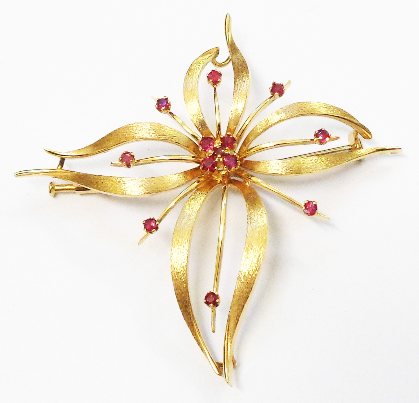 A 2 3/4" yellow metal stylised floral brooch, set with small rubies