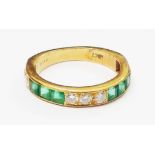 A marked 18ct. yellow metal band, set with three central diamonds, flanked by six paved emeralds and
