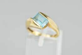 A 9CT GOLD TOPAZ RING, designed as a rectangular blue topaz in a cross over design setting with