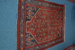 A 20TH CENTURY TURKISH WOOLLEN RED GROUND RUG, 194cm x 128cm, together with a Kashan style red